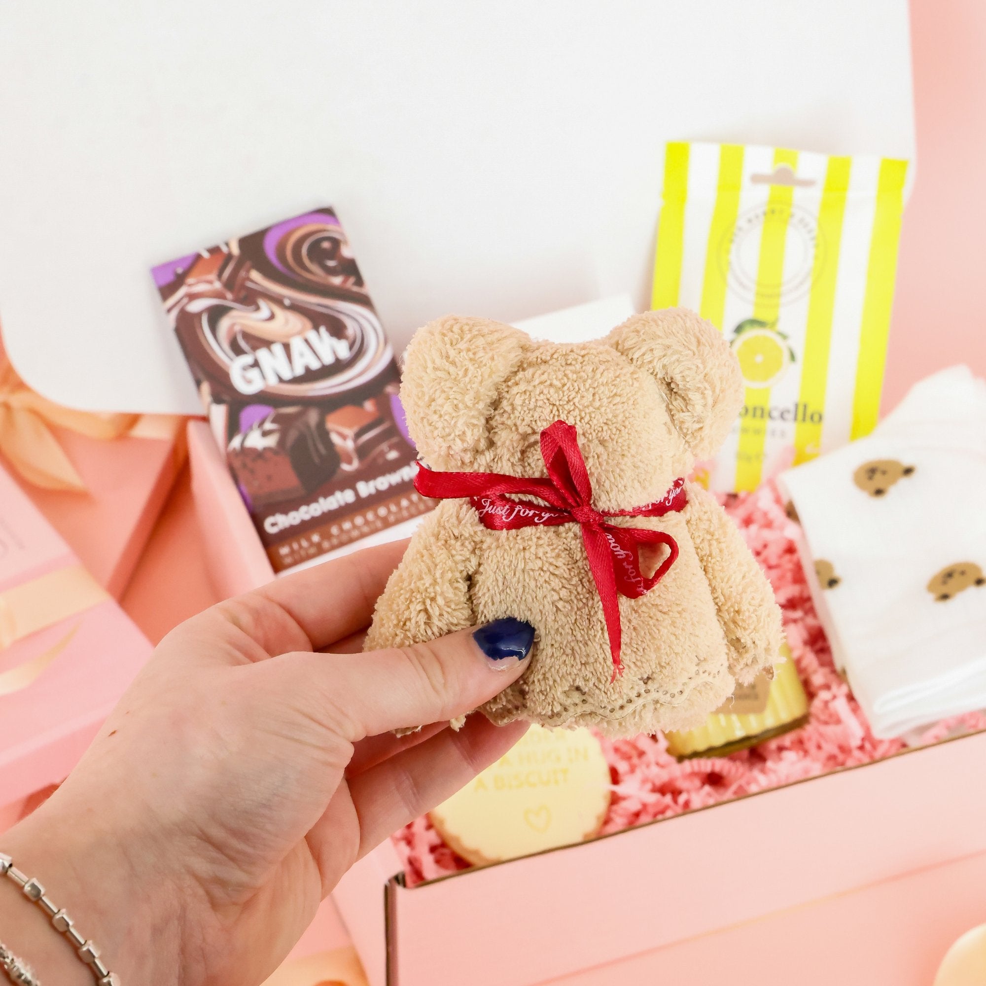 Small beige plush teddy bear towel included in a comfort gift set and mental health care package for sending a virtual hug to a friend.