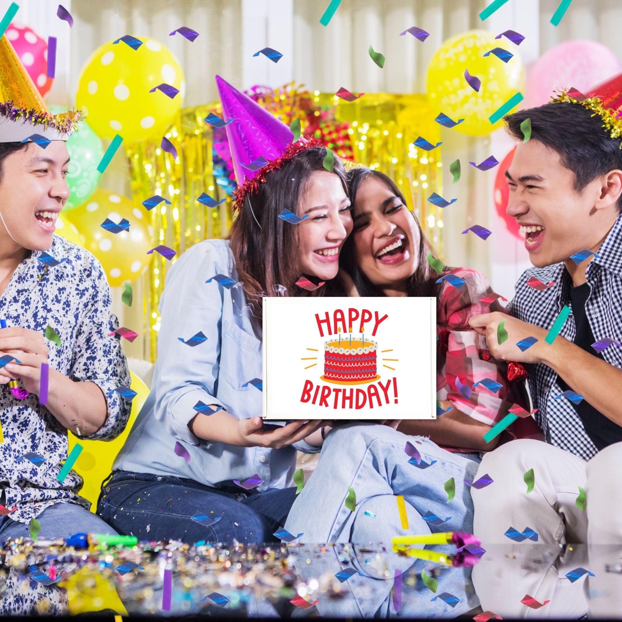 Group of friends celebrating birthday with party hats and confetti, holding a chocolate gift box that says Happy Birthday.