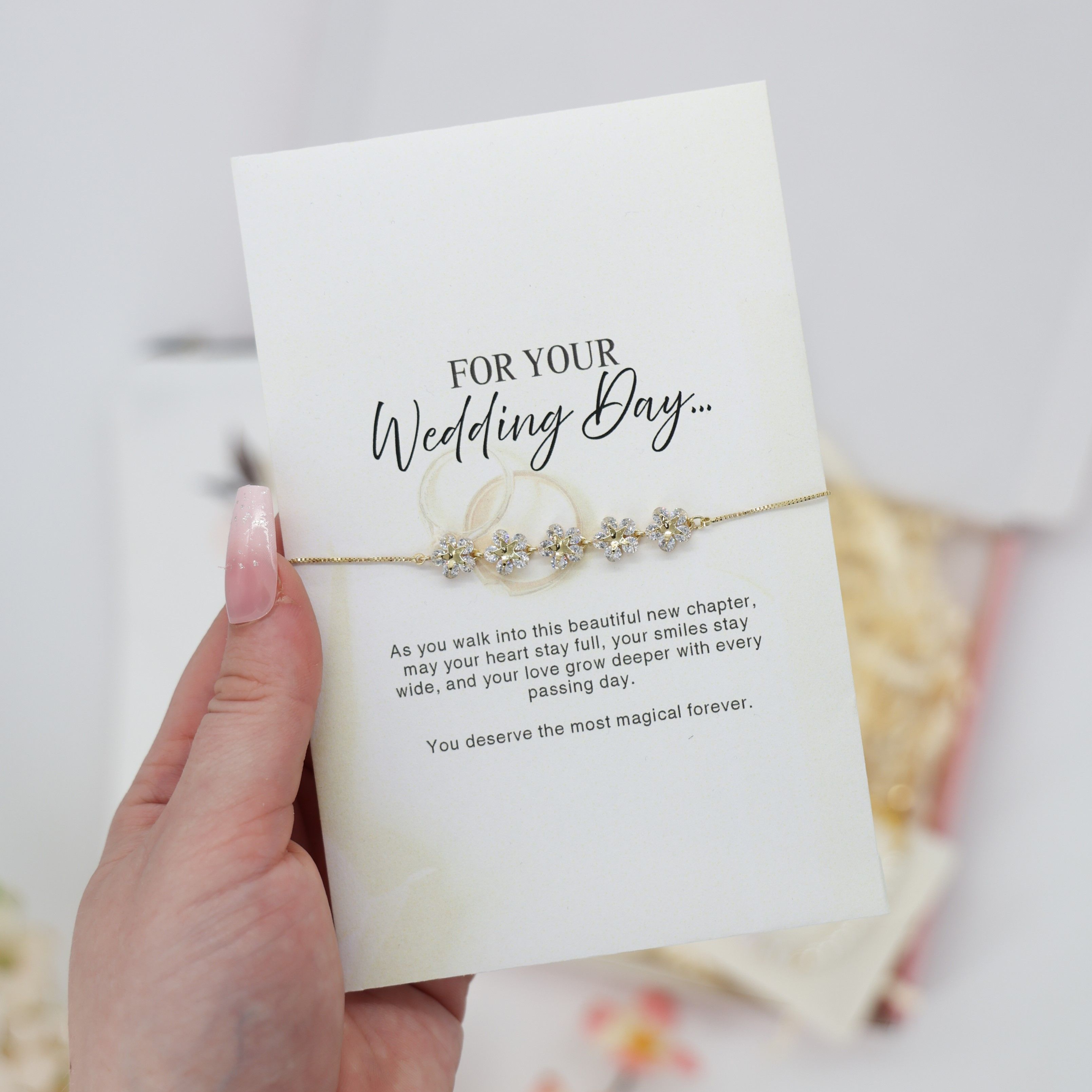 Hand holding card with gold chain bracelet, adorned with flower-shaped charms, titled FOR YOUR Wedding Day…. Part of A Little Gift for the Bride collection.
