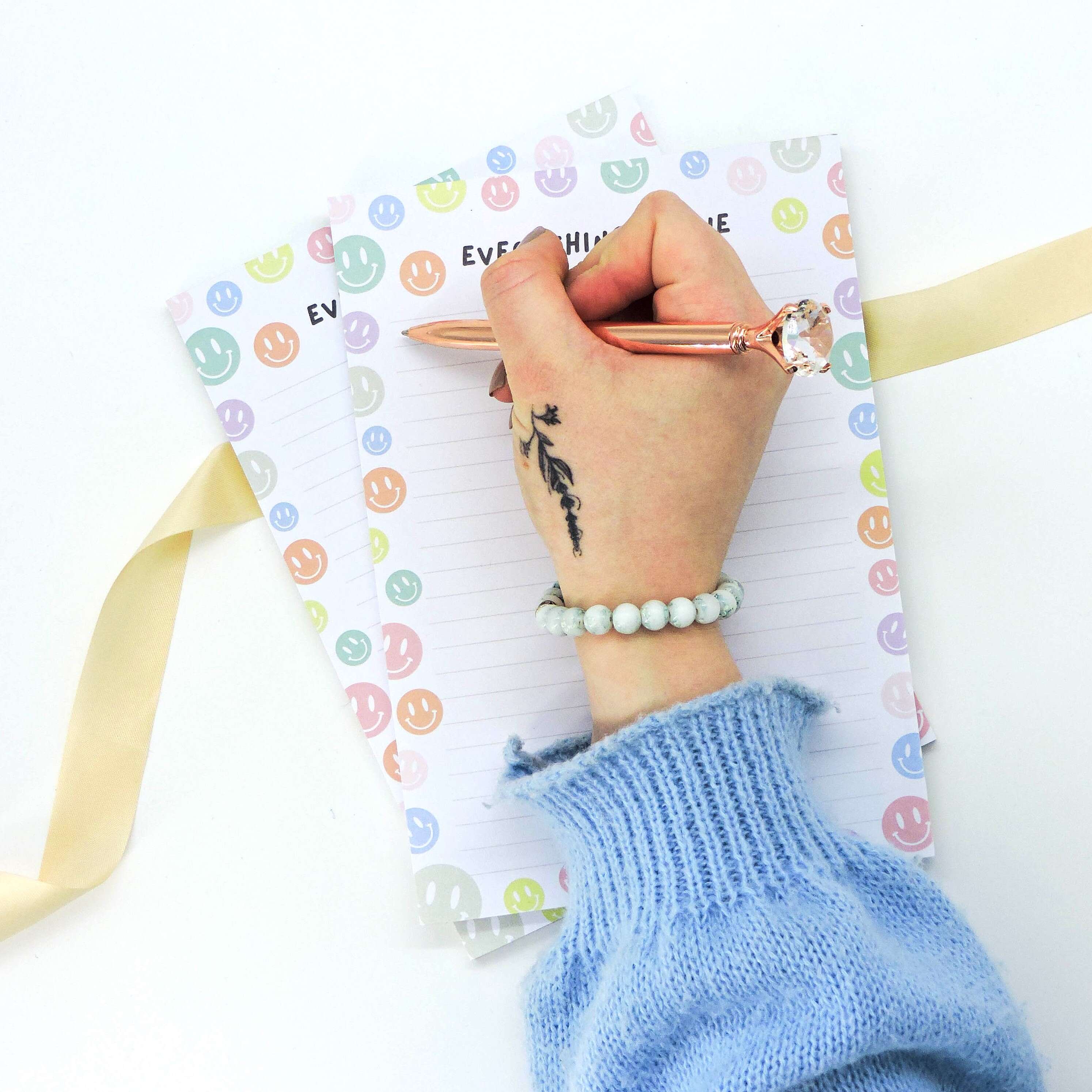 Hand holding the Everything is Fine A5 Deskpad with a smiley face border, ideal for notes and reminders, perfect for students and professionals.