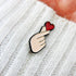 Heart Gesture Enamel Pin held in a hand, showcasing a charming heart design. Perfect for adding a sweet, affectionate touch to any gift.