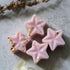 Lavender Wax Melt: Pink star-shaped soy wax melts, hand-poured, offering a calming lavender fragrance with eucalyptus, bergamot, patchouli, tonka, moss, and musk notes.