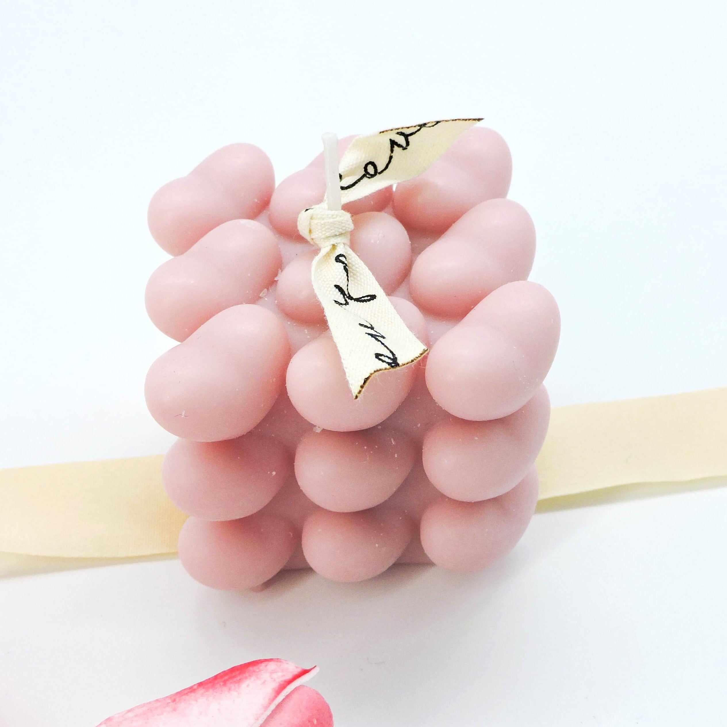Luxury Mini Hearts Candle – Pink, showcased with a close-up of its intricate bubble heart shape, accompanied by a finger adjusting the elegant white ribbon.
