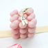 Luxury Mini Hearts Candle – Pink, showcased with a close-up of its intricate bubble heart shape, accompanied by a finger adjusting the elegant white ribbon.