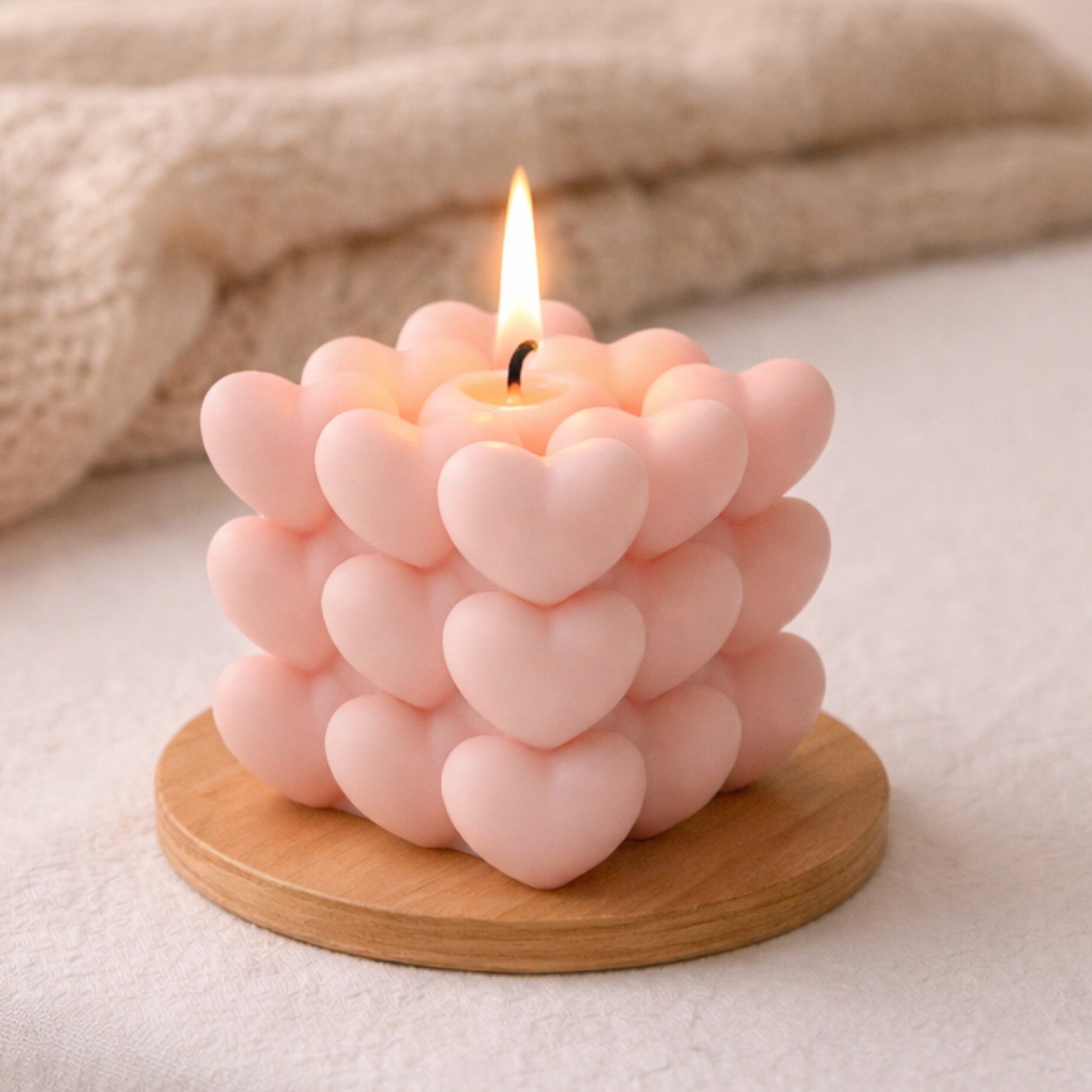 Luxury Mini Hearts Candle – Pink, showcased with a close-up of its intricate bubble heart shape, accompanied by a finger adjusting the elegant white ribbon.
