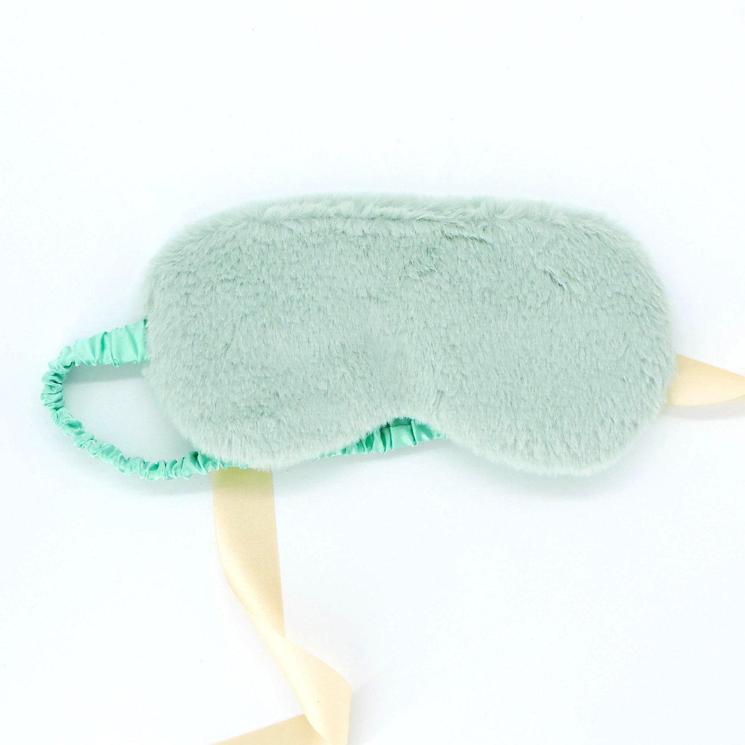 Plush Eye Mask - Green: A close-up of a plush sleep mask with a yellow ribbon, featuring a satin strap for a comfortable fit.