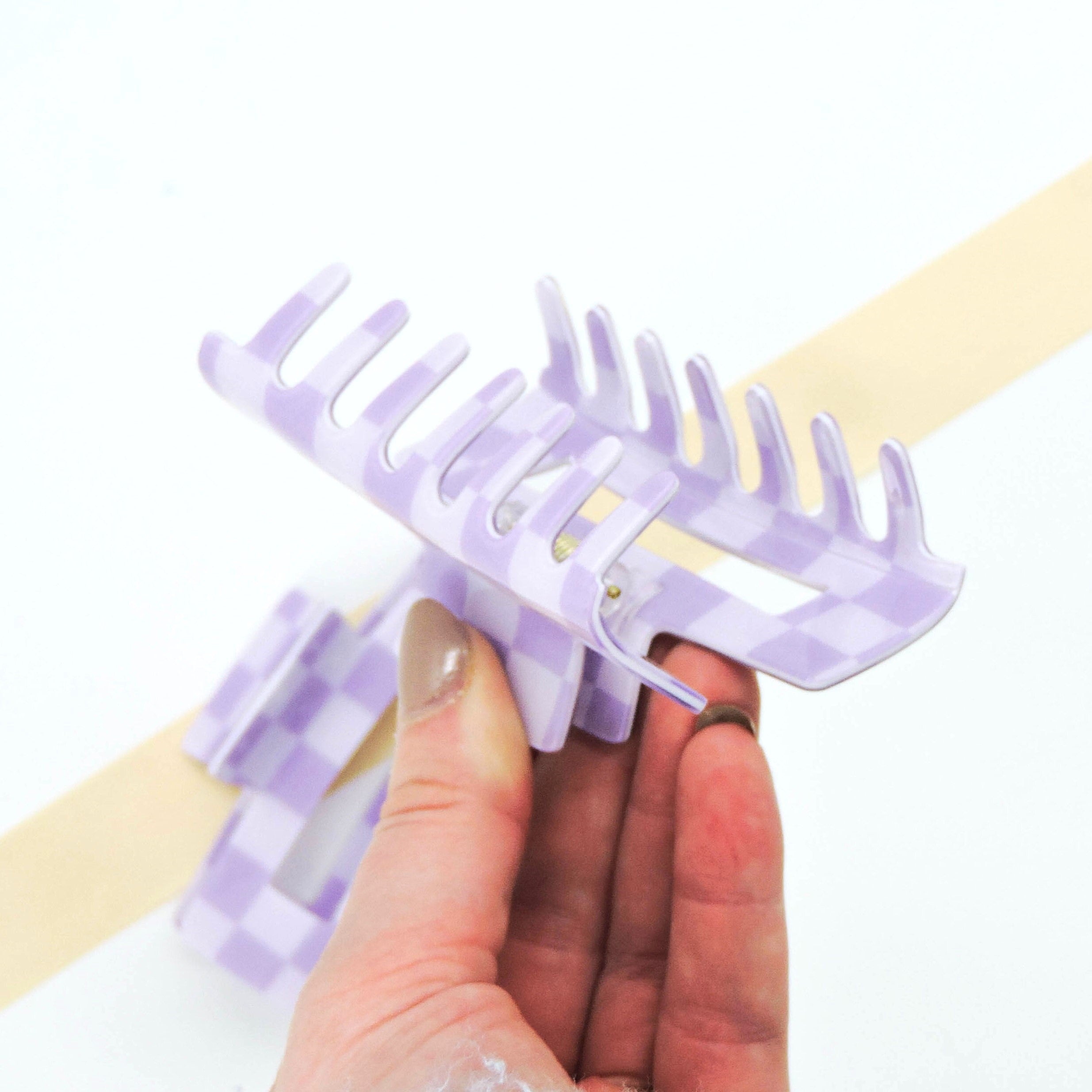 Hand holding Purple Checkered Big Claw Hair Clip, showcasing its sturdy design and trendy checkerboard pattern, perfect for securing and styling hair elegantly.