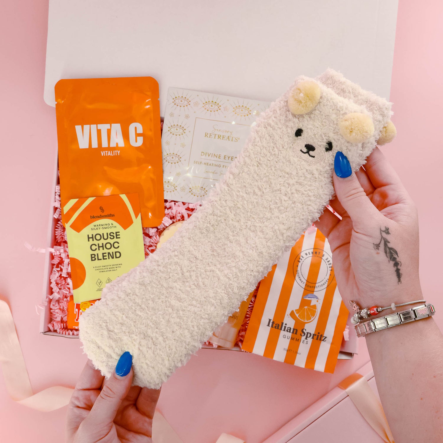 Rest and relax self care gift for her with fluffy bear socks, vitamin C face mask, eye mask, luxury treats and soothing pamper items.