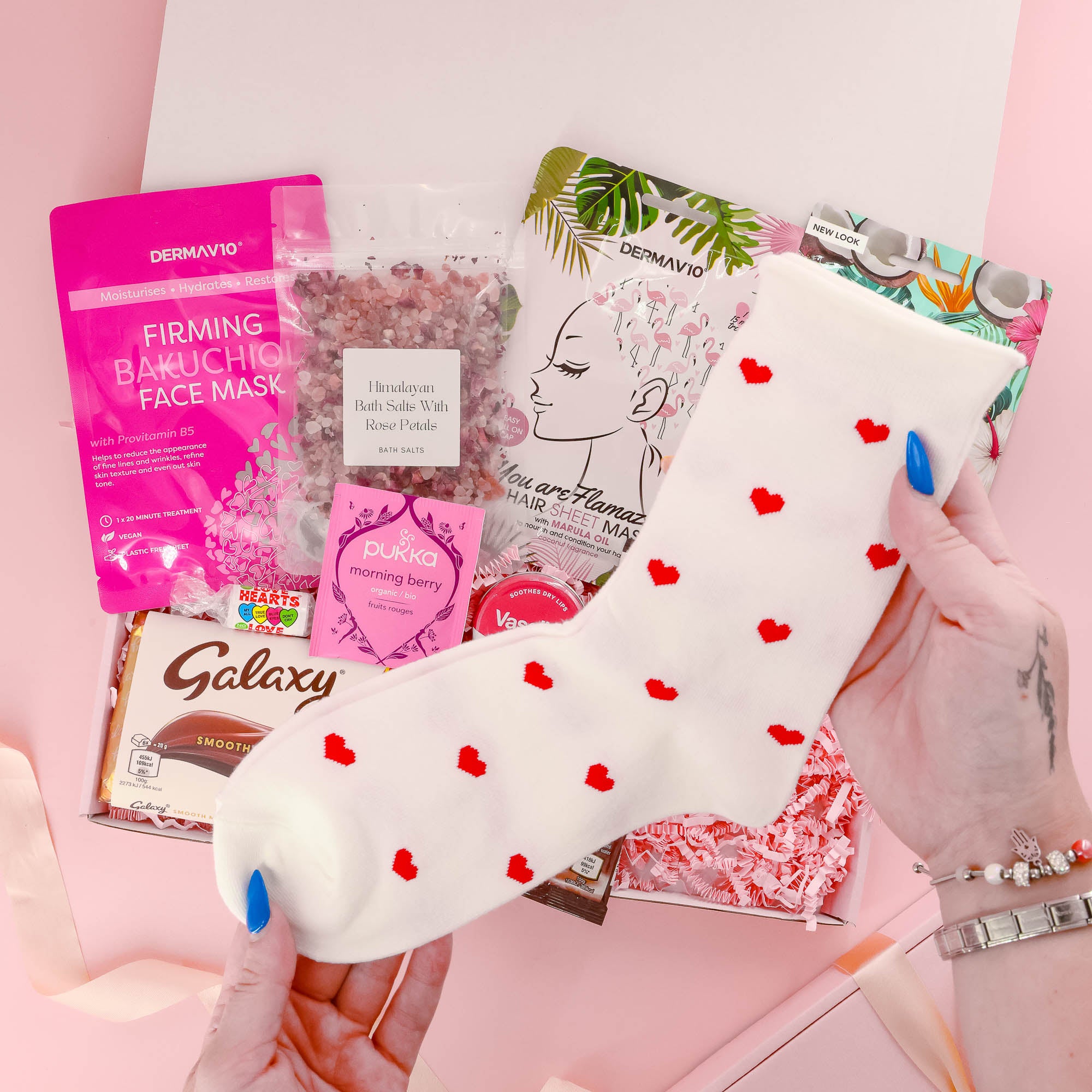 Cute and cozy self care gift for her with heart print socks, pampering treats, chocolate, and calming bath salts – the perfect hug in a box.