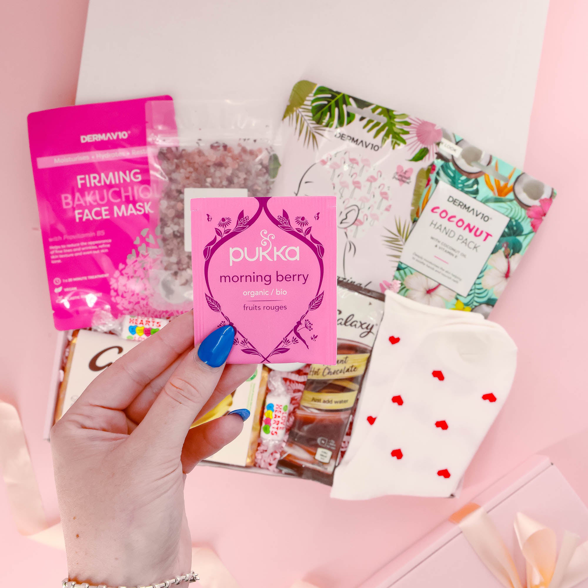 Thoughtful self care gift hamper for her with organic herbal tea, chocolate, pamper socks, face mask, and relaxing bath treats.