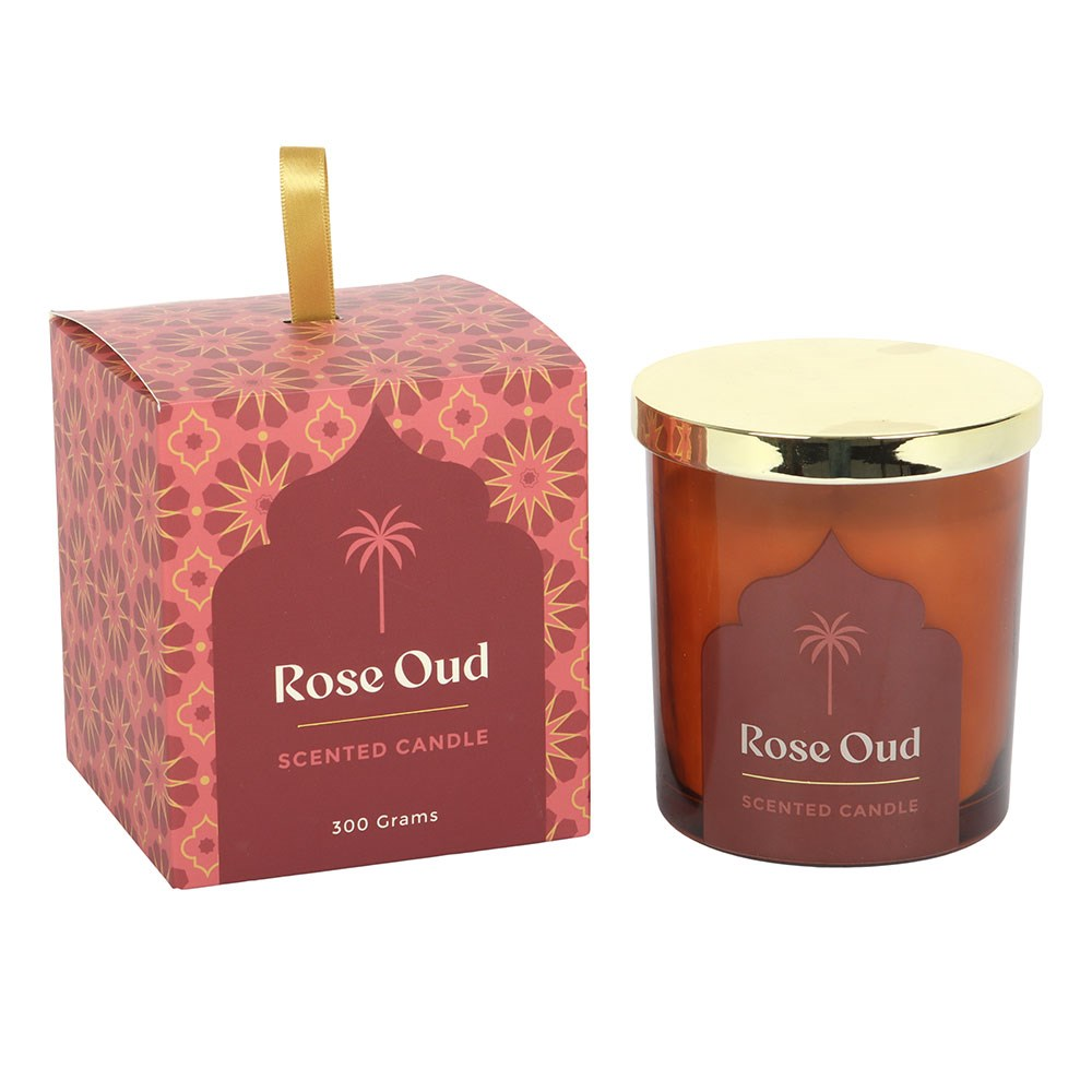 Rose Oud scented glass candle with warm glowing flame and decorative gold lid