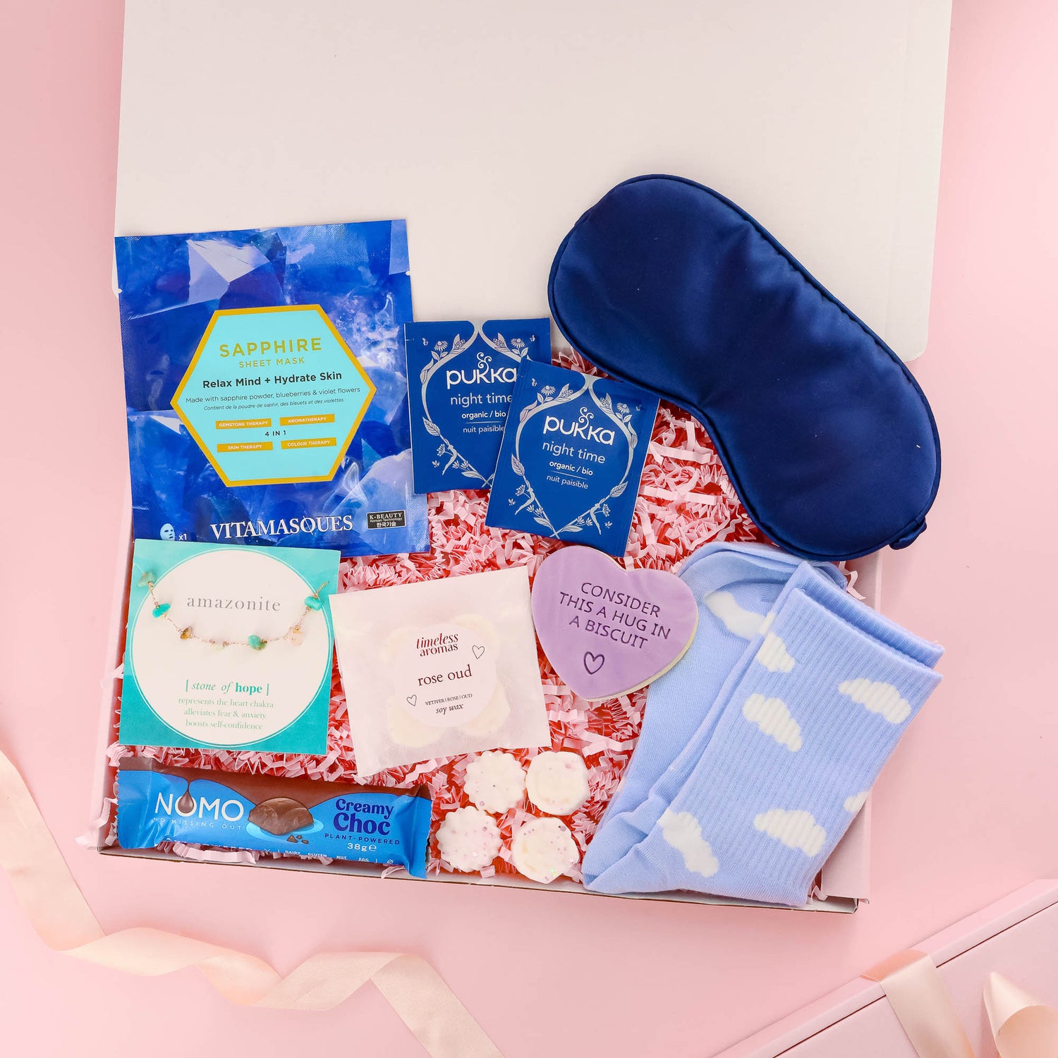 Complete self care gift box for her with herbal tea, cloud socks, sheet mask, bracelet, sleep mask, biscuit treat, and vegan chocolate – a relaxing gift for any occasion.