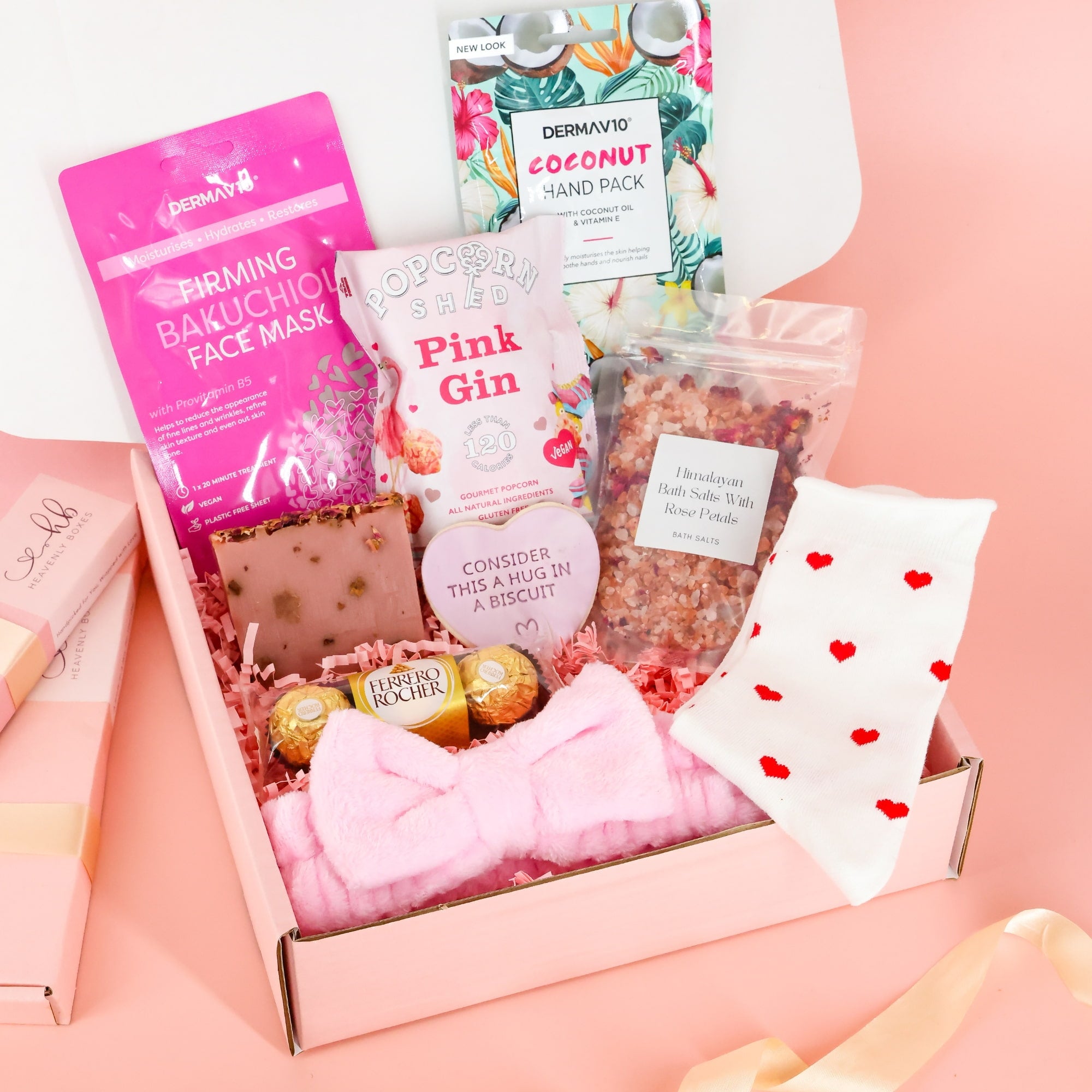 Pink pamper hamper self-care gift box for women featuring a face mask, Himalayan bath salts, pink gin popcorn, and heart-print socks.