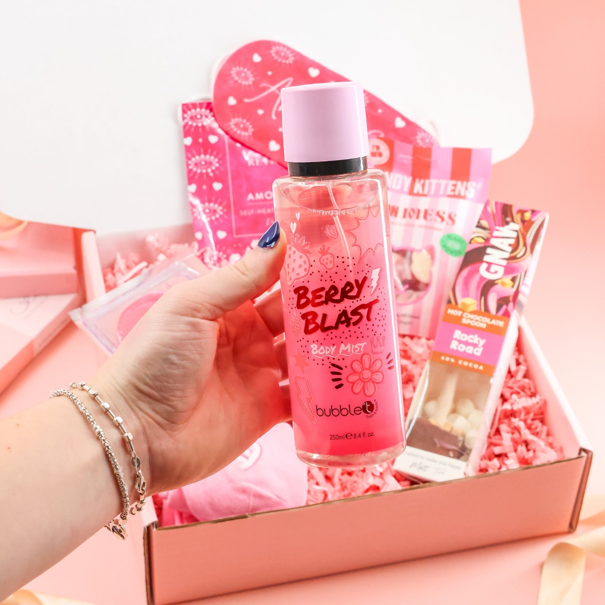 Hand holding Bubble T Berry Blast body mist, a featured item in the ultimate pink self-love gift box and luxury wellness care package.