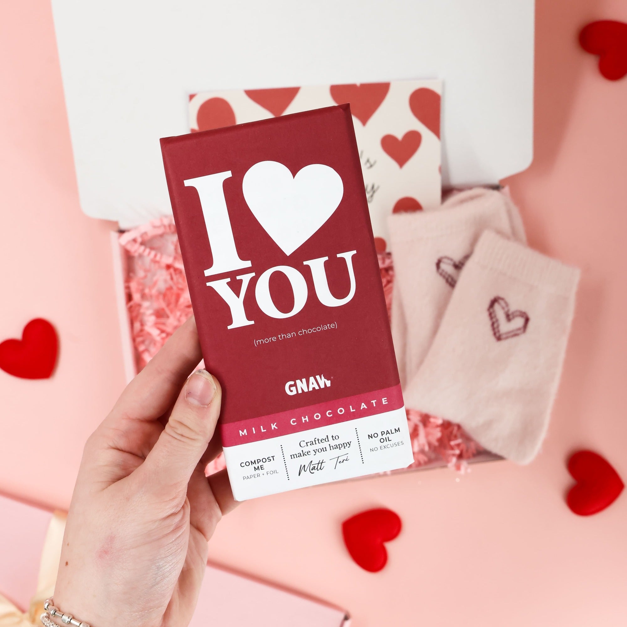 Valentines letterbox gift by Heavenly Boxes styled with heart socks, chocolate bar, biscuit, and love themed card