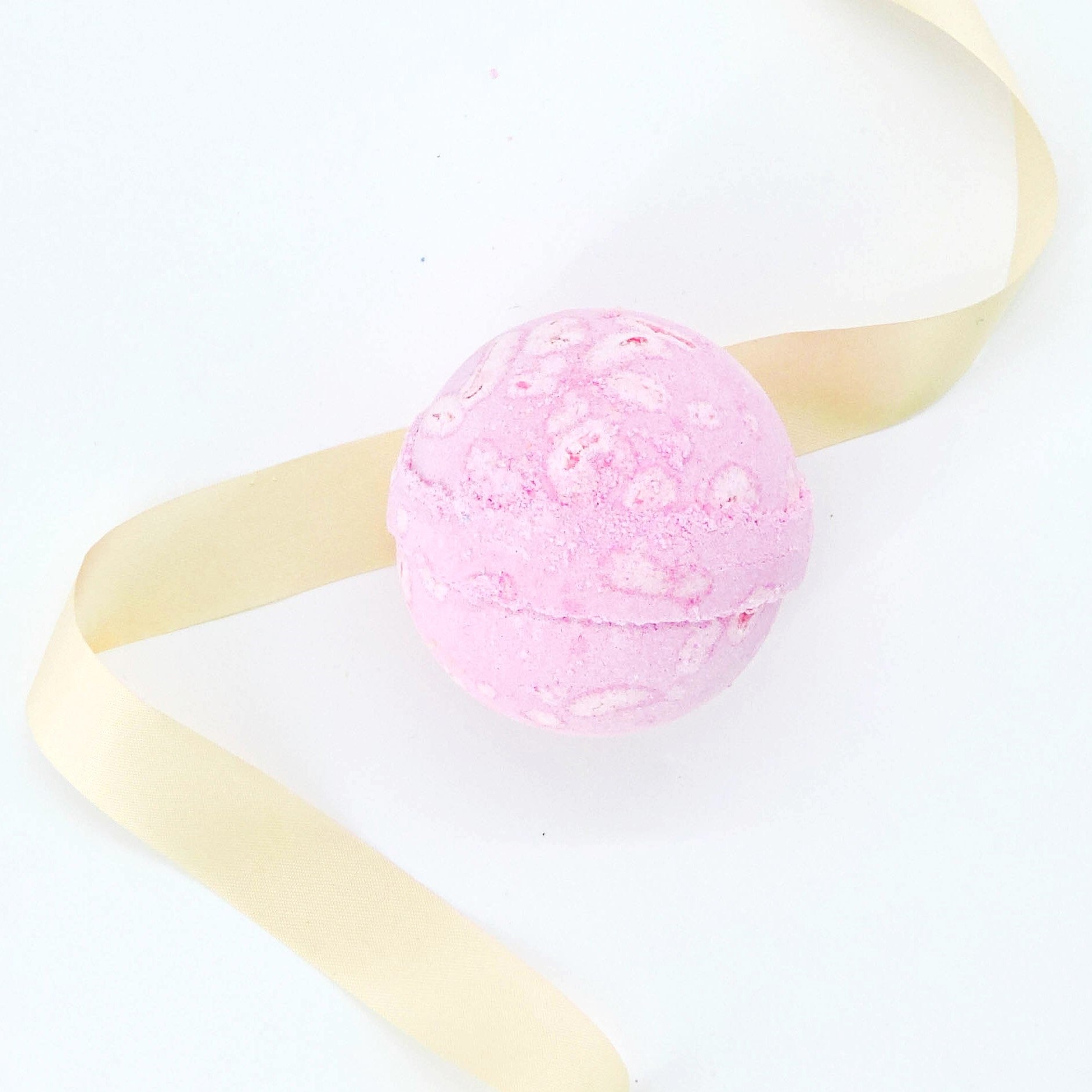Watermelon Tropical Coco Bath Bomb adorned with a yellow ribbon, promises a watermelon scent and coconut oil for a refreshing, luxurious bath experience.
