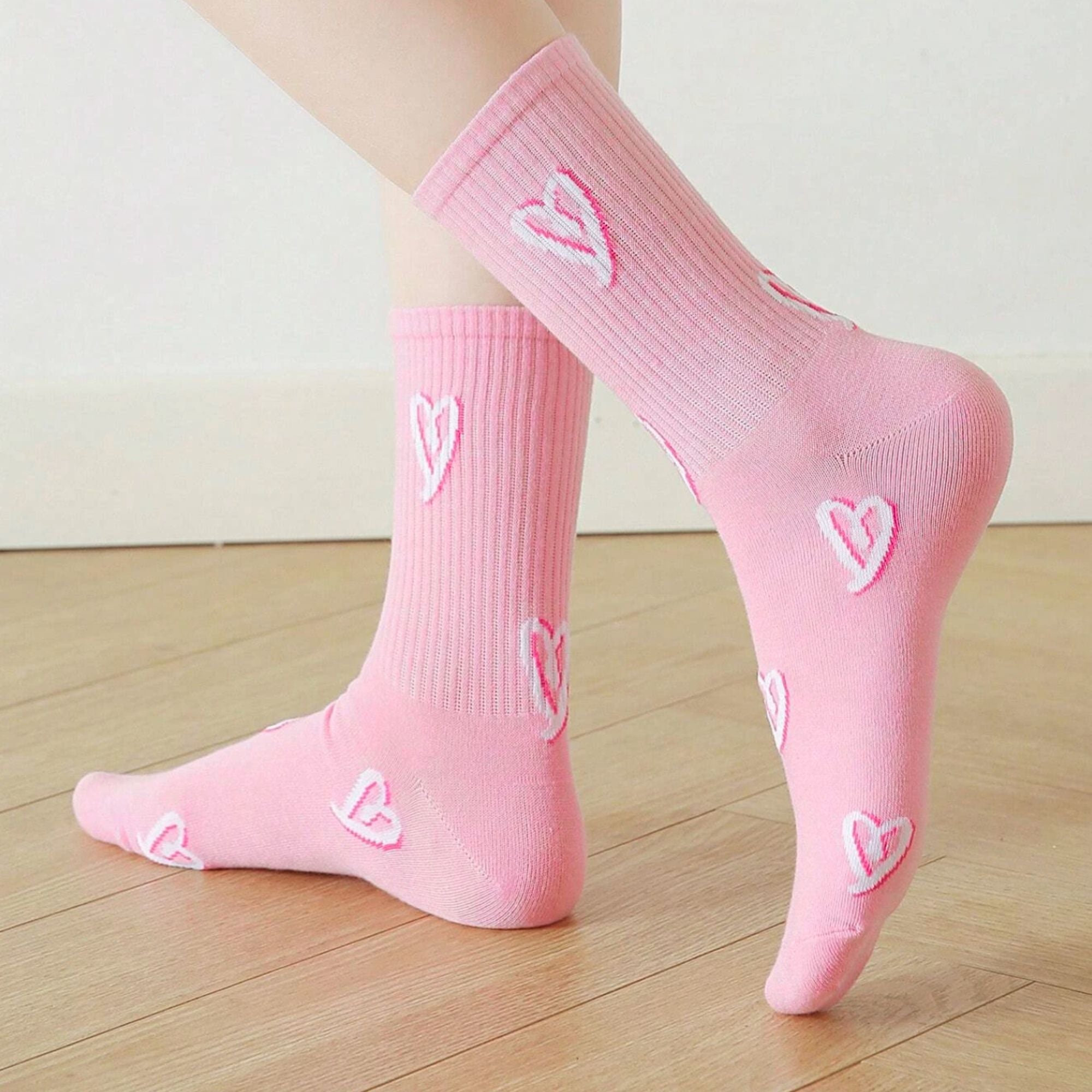 Heart Print Socks - Pink: Feet wearing socks with embroidered white hearts on soft pink fabric, blending playful style with cosy functionality. Ideal for gift boxes.