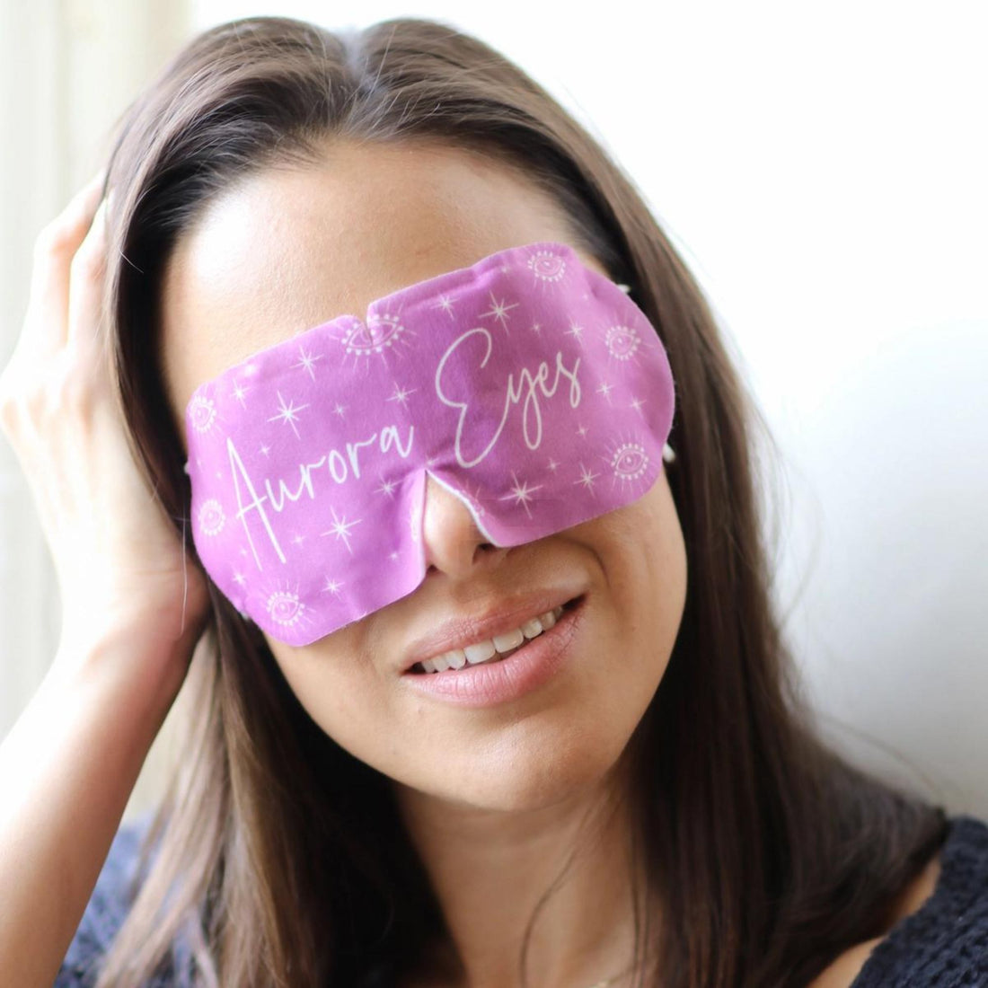 Close-up of a woman smiling, showcasing the Aurora Eye Mask, a subtle, fragrance-free, vegan product designed to relieve headaches and stress.