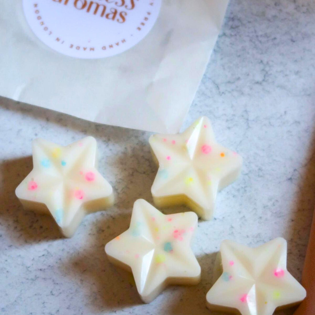 Birthday Cake Wax Melt in a star shape, resembling a white candy, offering a sweet bakery scent, perfect for adding warmth to any birthday celebration.