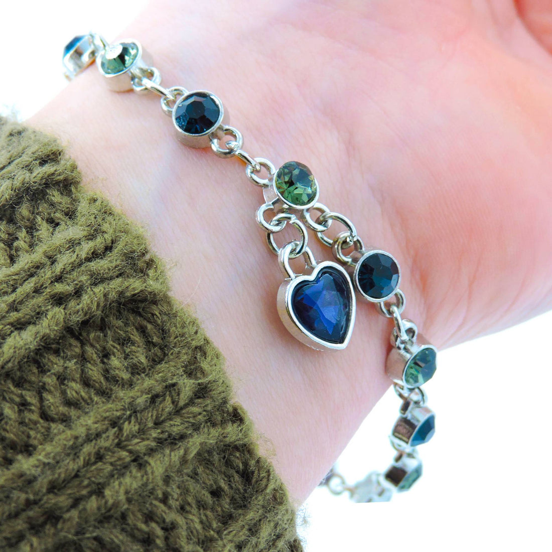 Blue Heart of the Ocean Bracelet on wrist, showcasing linked blue and green crystals with a heart-shaped charm, exuding timeless elegance and sparkle.