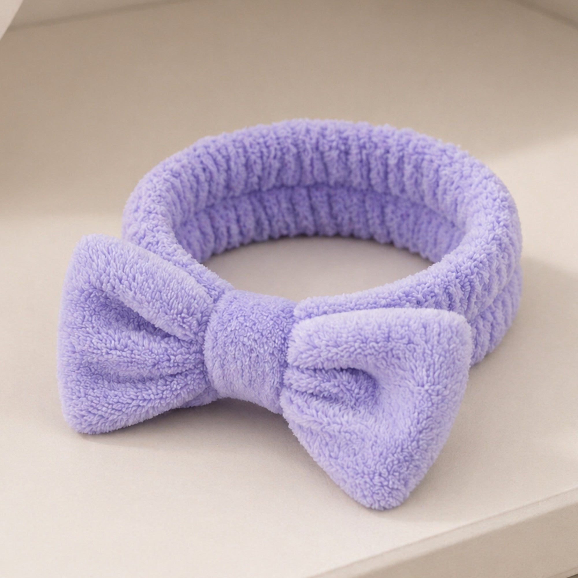 Bowknot Headband Purple: A plush, stylish headband with a bow, perfect for securing hair during beauty routines, blending functionality with fashion.