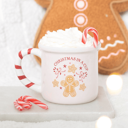 Pink ceramic Christmas mug with red and white candy cane striped handle and festive gingerbread illustration