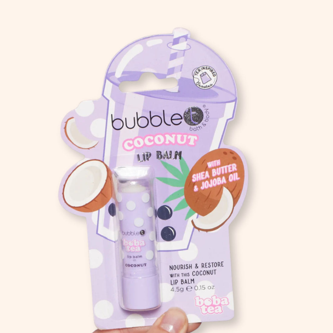 Hand holding a package of Coconut Lip Balm, highlighting its compact size. Formulated with Shea Butter and Jojoba Oil for hydration and protection.