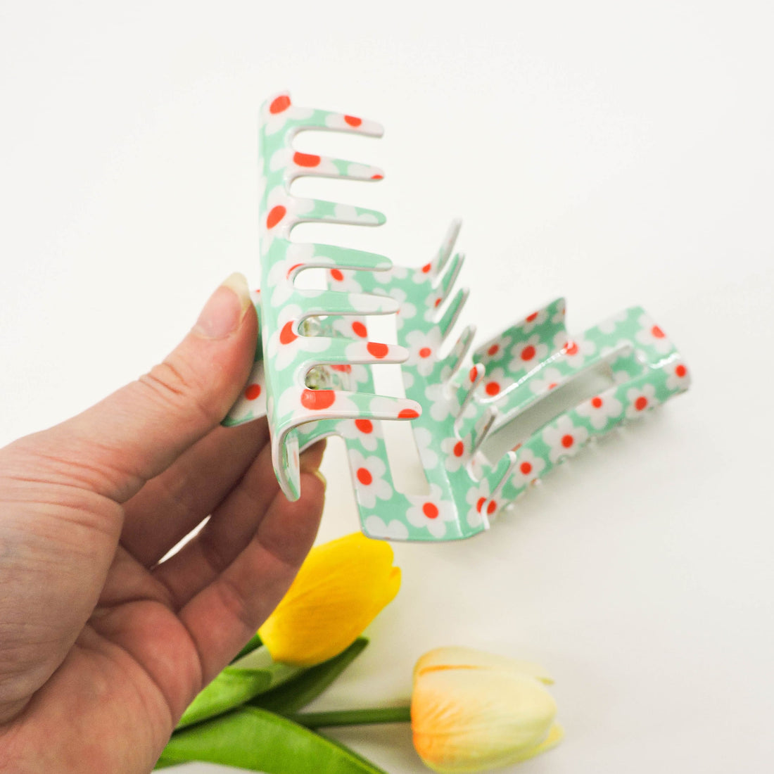 Flower Print Hair Clip held in hand, showcasing its secure grip and chic floral pattern for stylish hair styling.