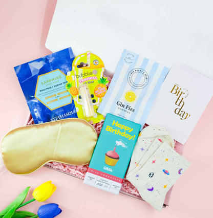 Gin Fizz Birthday Box filled with pampering treats, tropical bath bomb, gold satin sleep mask, birthday chocolate, face mask and gin fizz sweets – fun birthday gift for her