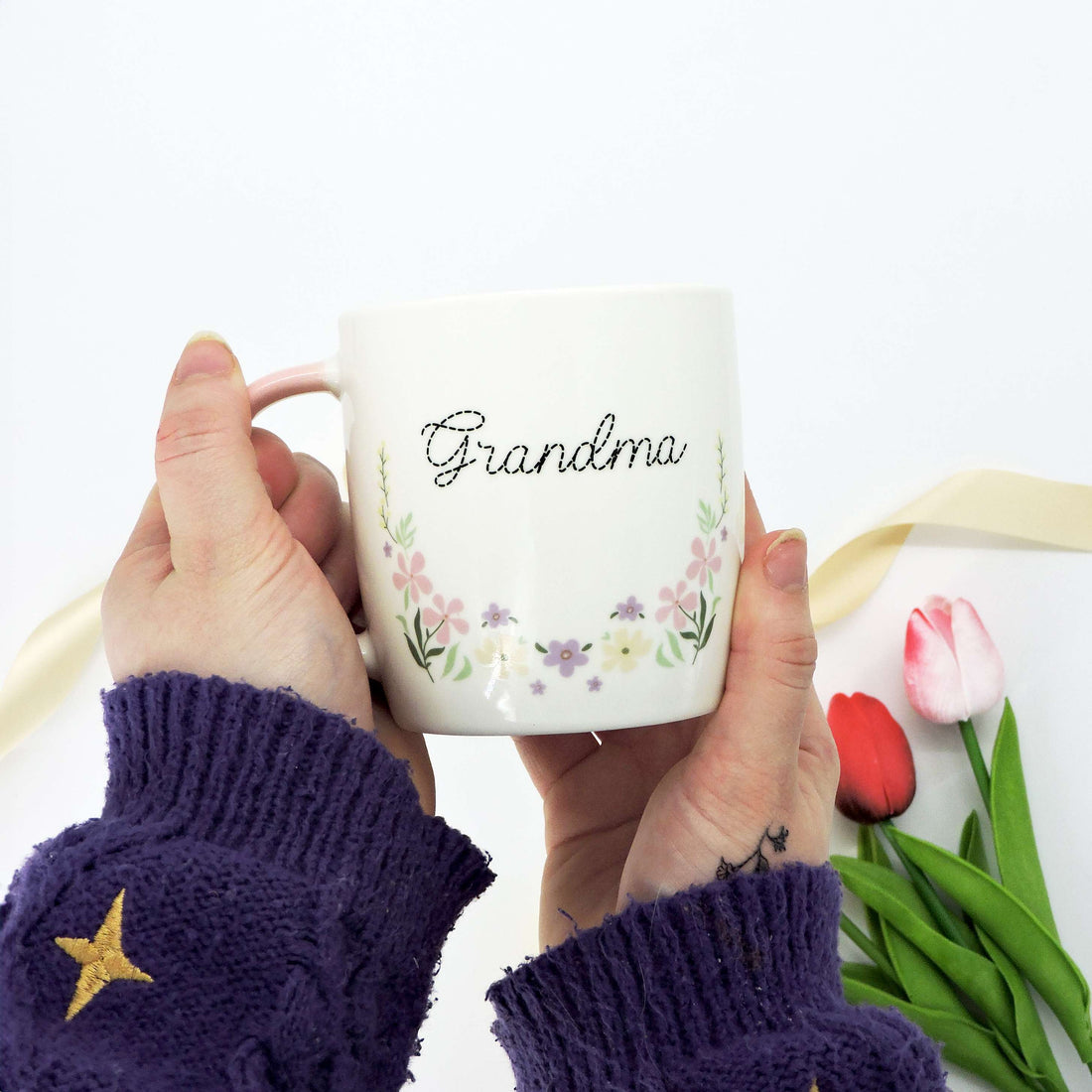 Grandma Ceramic Mug with floral design and soft pink handle, held by a person, showcasing its elegant and heartfelt gift appeal for a beloved grandmother.