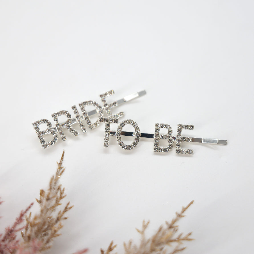 Bride To Be Crystal Hair Pins with silver-toned rhinestones spelling “BRIDE” and “TO BE,” perfect for bridal events, offering a bold, elegant touch.