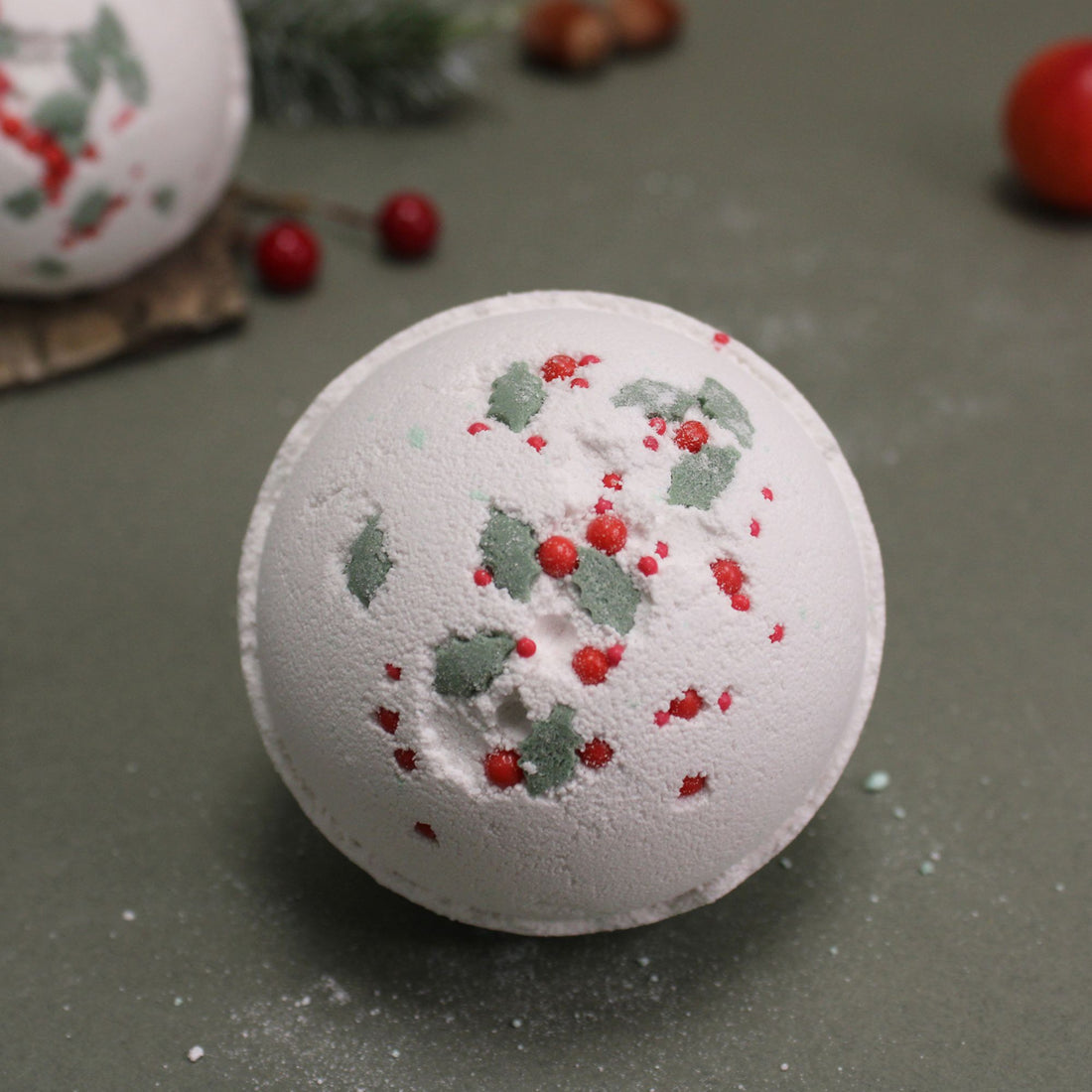 Holly Berry &amp; Mistletoe Bath Bomb with red and green sprinkles, offering a festive, fragrant soak enriched with essential oils for a luxurious bath experience.