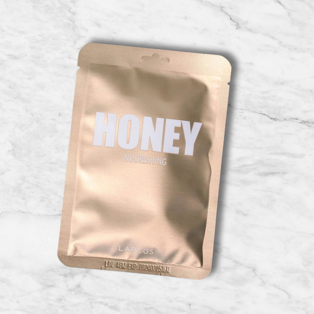 Honey Nourishing Mask label close-up on a brown surface, highlighting its skin-moisturizing and antibacterial benefits for treating acne, eczema, and psoriasis.