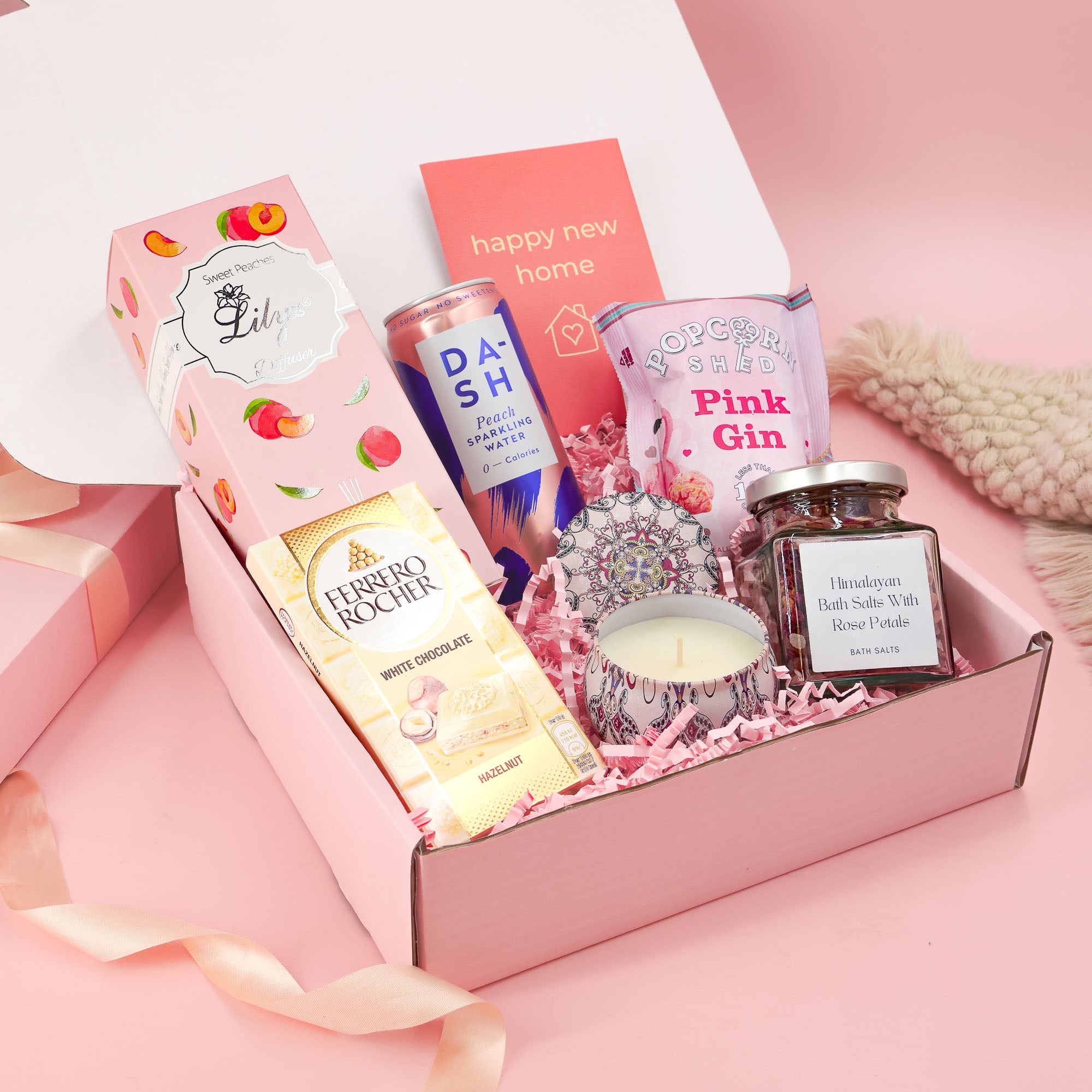 custom made Gift box ideal gift for her with various items including a Ferrero Rocher chocolate, a candle, and a pink Gin bottle on a pink background.