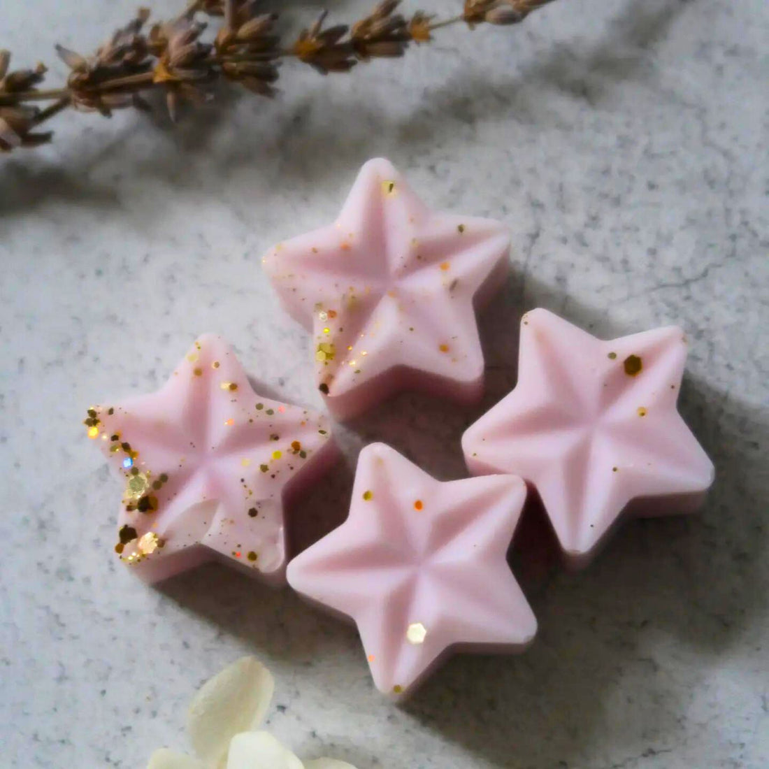 Lavender Wax Melt: Pink star-shaped soy wax melts, hand-poured, offering a calming lavender fragrance with eucalyptus, bergamot, patchouli, tonka, moss, and musk notes.