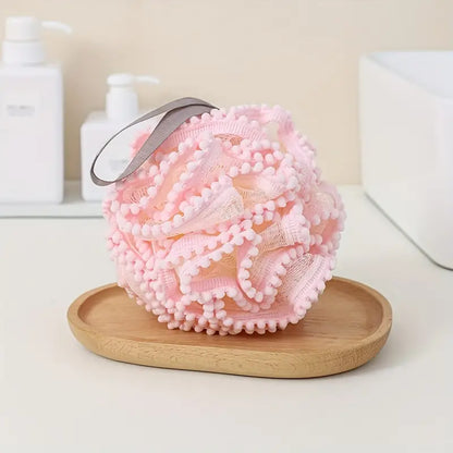 Luxury Loofah - Pink displayed on a wooden dish, showcasing its soft texture designed for gentle exfoliation and a rich, luxurious lather experience.
