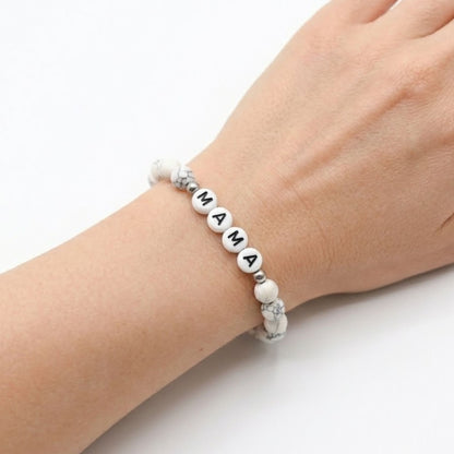 Mama Bracelet with white marbled beads and black letter charms, designed as a stretch-fit fashion accessory celebrating motherhood. Ideal gift for moms and mothers-to-be.