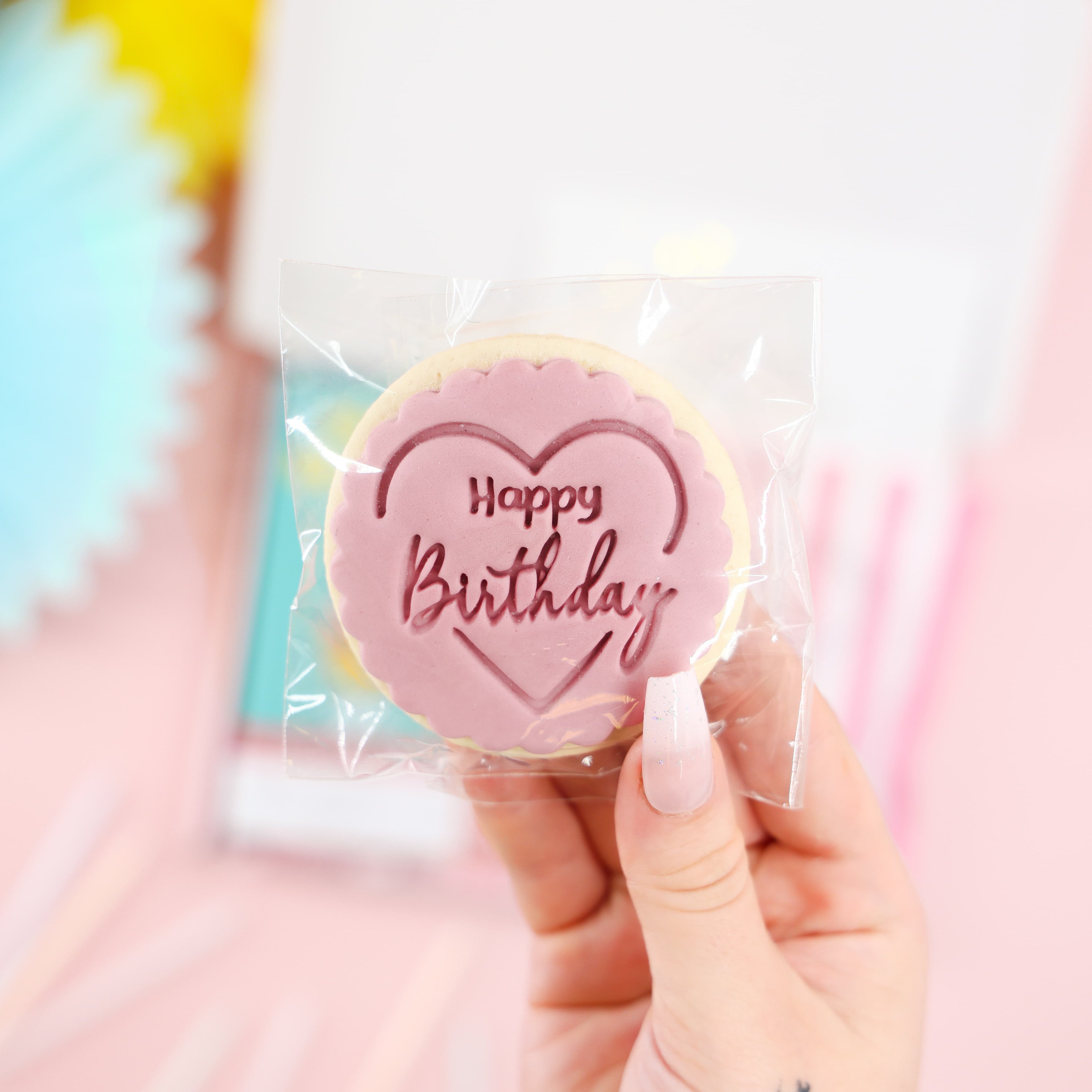 Close-up of iced Happy Birthday biscuit in pink heart design – part of the Mini Birthday Indulgence Gift Box.