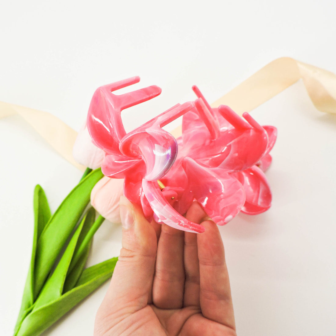Hand holding Pink Flower Hair Clip with petal design, showcasing its sturdy grip, ideal for adding elegance to hairstyles for any occasion.
