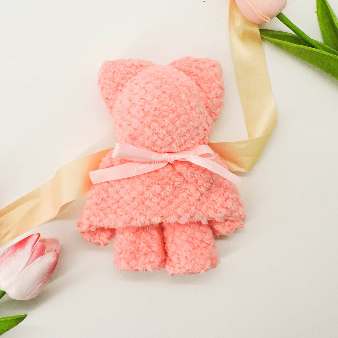 Pink Teddy Face Cloth with a ribbon, featuring a plush microfiber texture, ideal for gentle skin cleansing and adding a cute touch to your routine.