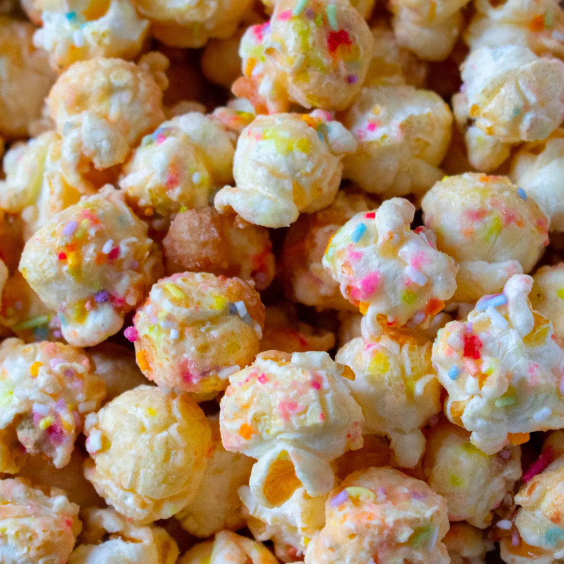 Birthday Cake Popcorn Bonanza: a festive pile of popcorn topped with colorful sprinkles, offering a delightful snack experience for celebrations. Vegetarian-friendly confectionery.