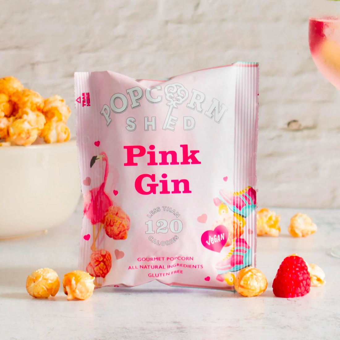 Pink Gin Popcorn next to a bowl, highlighting crunchy air-popped corn with raspberry and lime-infused caramel, capturing a unique gin and tonic flavor experience.