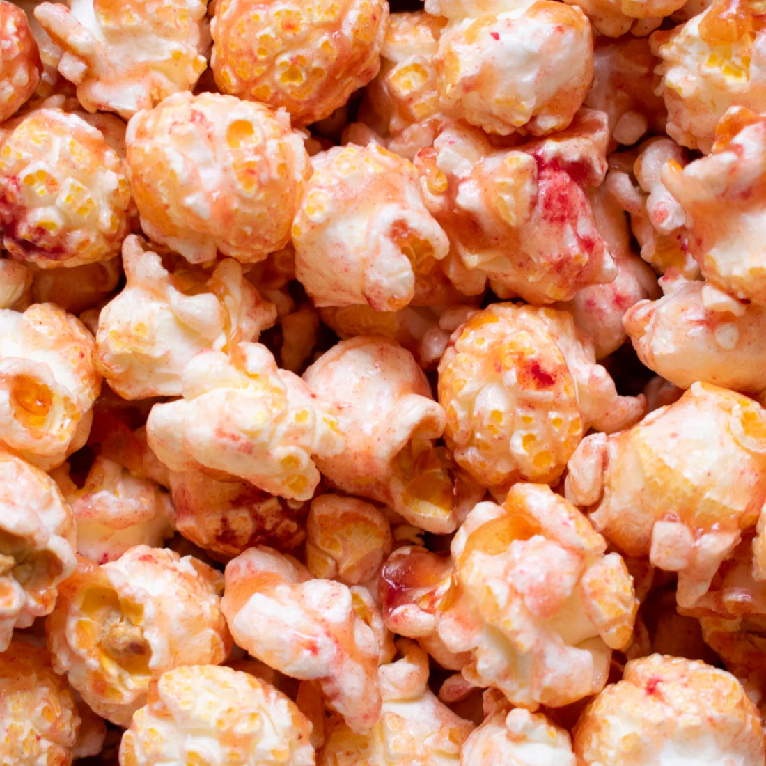 Close-up of Pink Gin Popcorn, showcasing air-popped corn coated in pink gin-infused caramel with raspberry and lime hints, highlighting its crunchy texture and unique flavor.