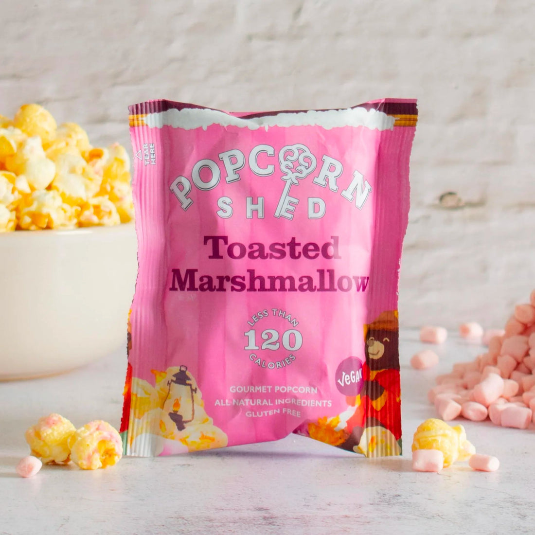 Toasted Marshmallow Popcorn: A pink packet containing crunchy caramel popcorn and gooey marshmallows, offering a vegan, gluten-free snack perfect for adventures.