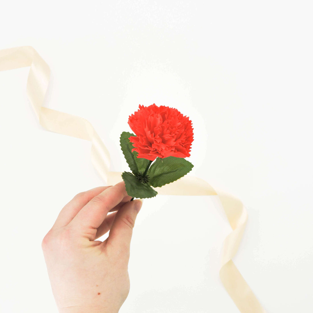 Hand holding a Red Carnation Soap Flower, a handcrafted soap designed to dissolve into fragrant lather, perfect for enhancing bath time luxury.