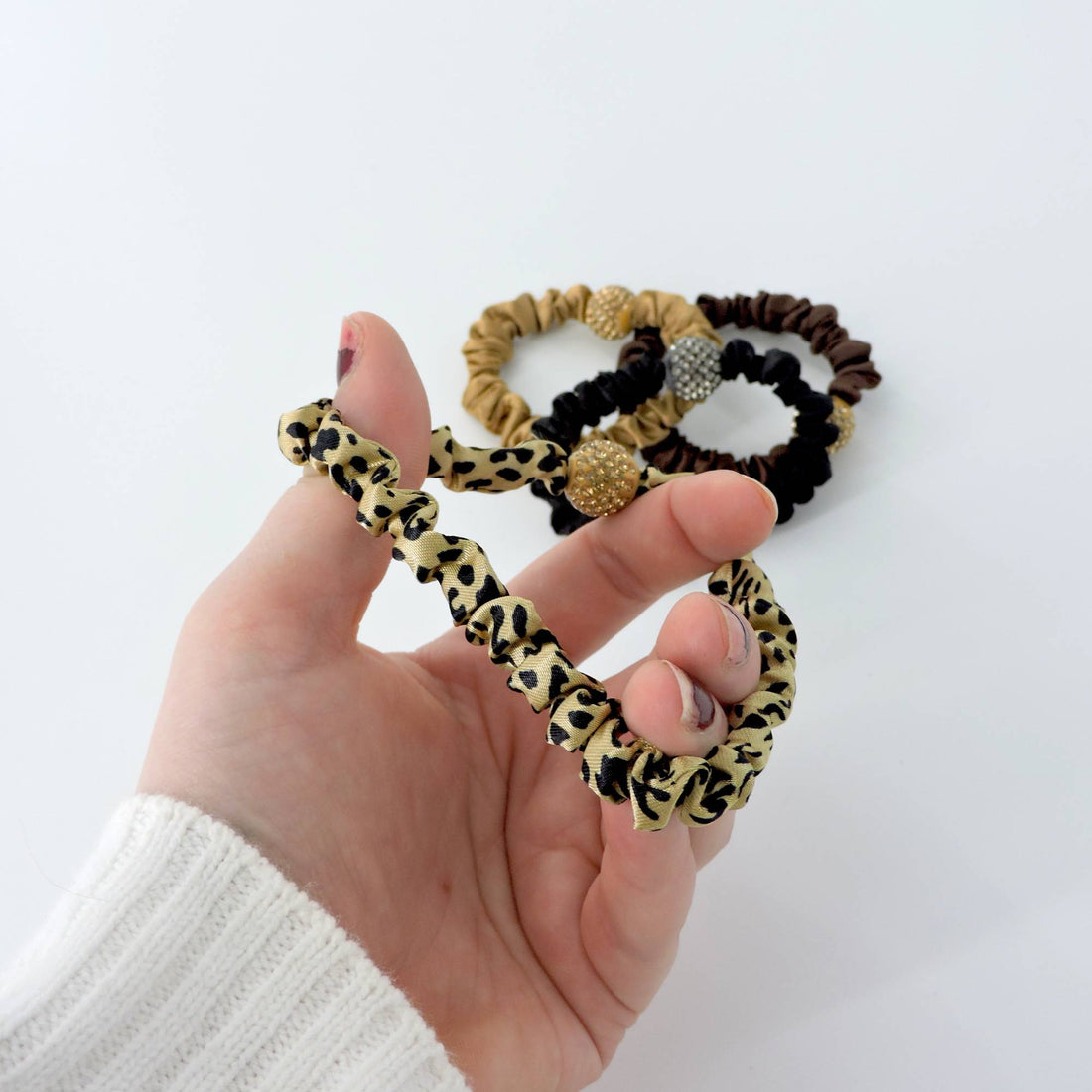 Rhinestone Leopard Hair Scrunchie - 4pcs features chic animal prints and rhinestone accents, held in hand, showcasing its stylish elegance and practicality.