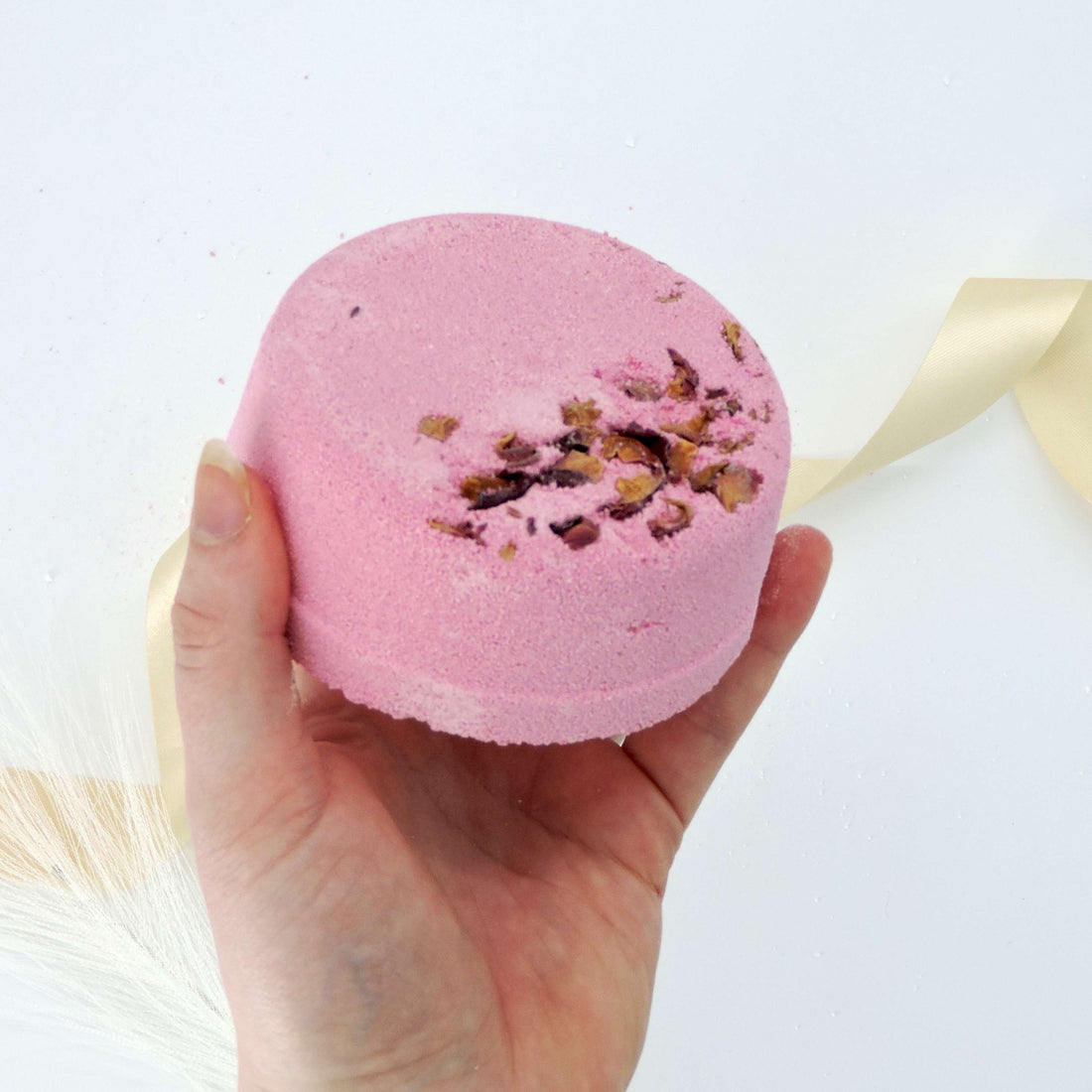 Hand holding a Rose, Lavender, Patchouli Bath Bomb, highlighting its spherical shape and texture, perfect for relaxation and tension relief.