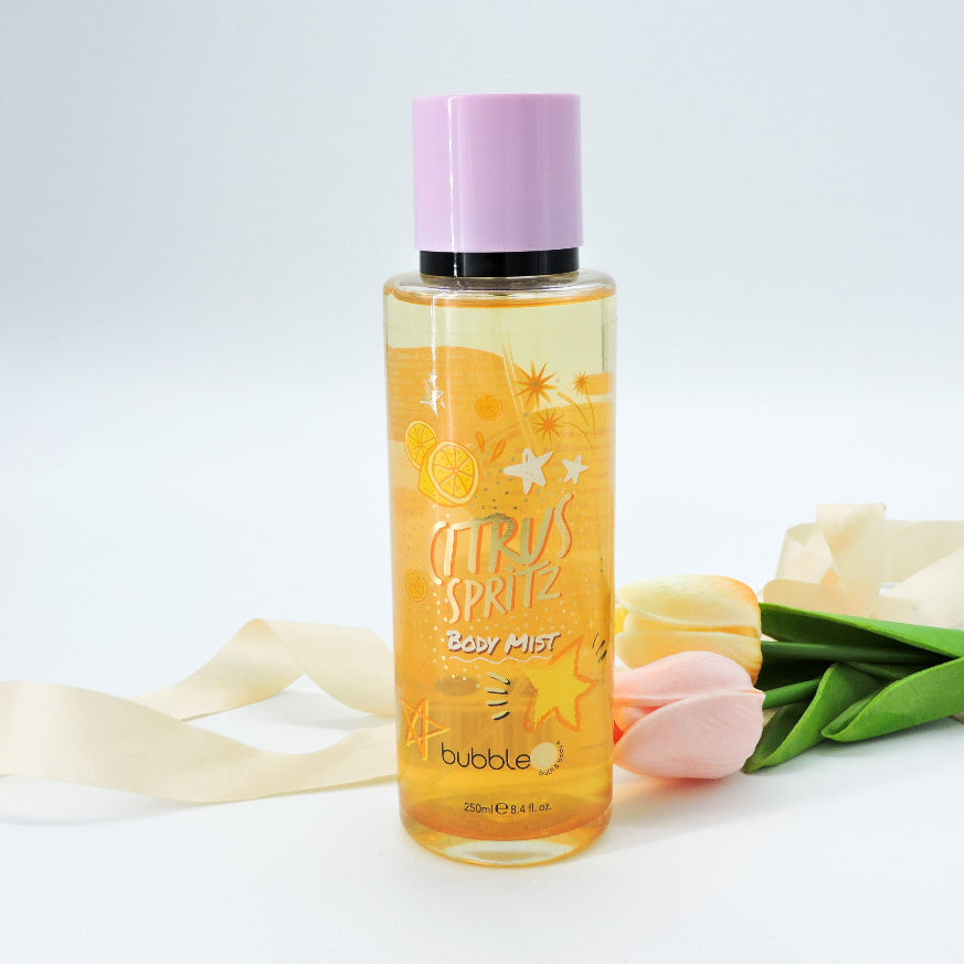 Citrus Spritz Body Mist bottle close-up next to tulips, highlighting its vibrant, refreshing essence for a cheerful, aromatic boost.