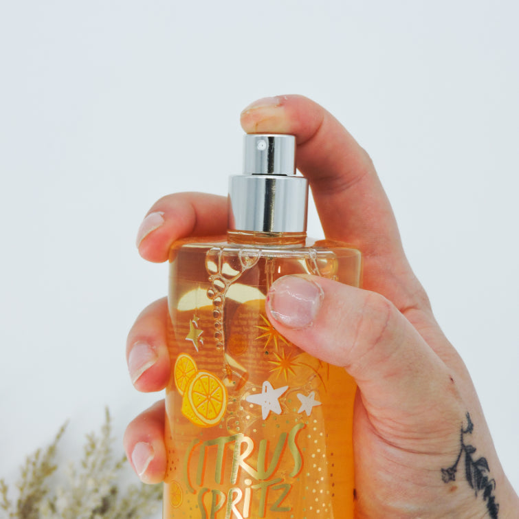 Citrus Spritz Body Mist held in hand, showcasing the bottle containing a vibrant, refreshing blend of orange and lemon scents for an uplifting experience.