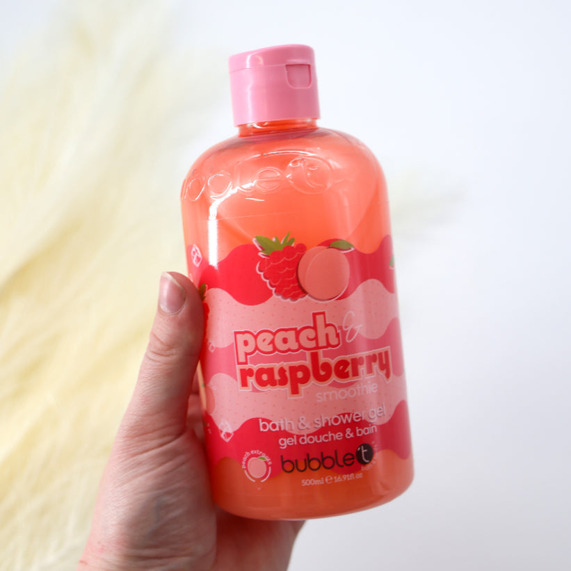Hand holding a bottle of Peach &amp; Raspberry Shower Gel, a fruity bath and shower product that creates a creamy, smoothie-like foam for soft, fragrant skin.